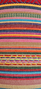 Close-up van het kleurrijke geweven textiel met roze, rood, blauw, groen en oranje.