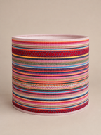 Losse kleurrijke lampenkap met horizontale strepen, geometrische patronen en roze biezen.