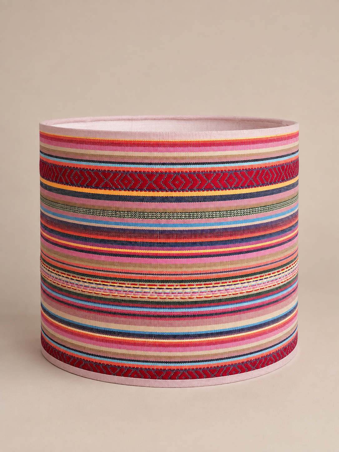 Losse kleurrijke lampenkap met horizontale strepen, geometrische patronen en roze biezen.