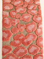 Detail van zalmroze jacquardstof met zacht reliëfpatroon op goudkleurige geweven ondergrond