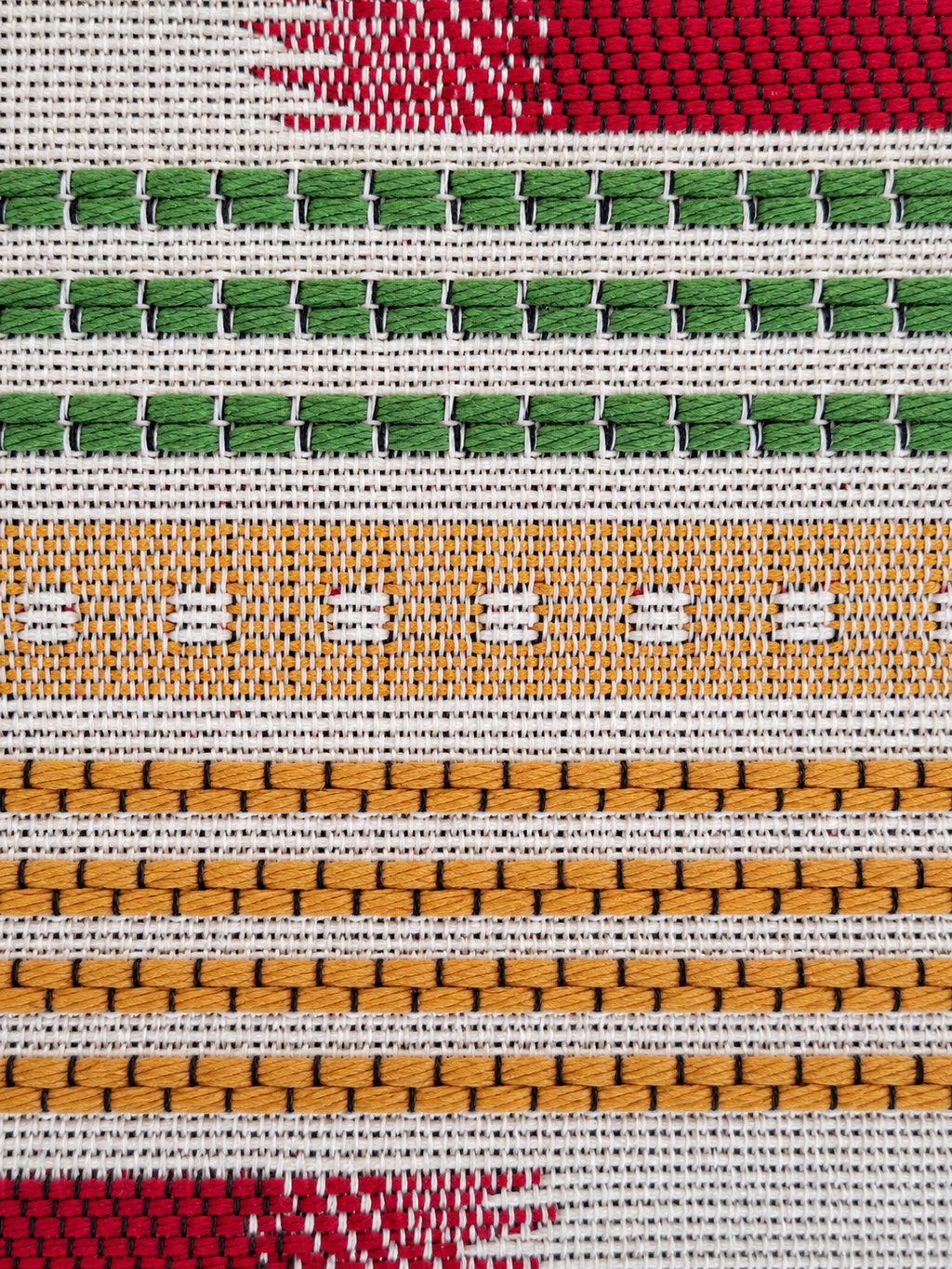 Detail geweven stof in groen, bordeauxrood, crème en oker