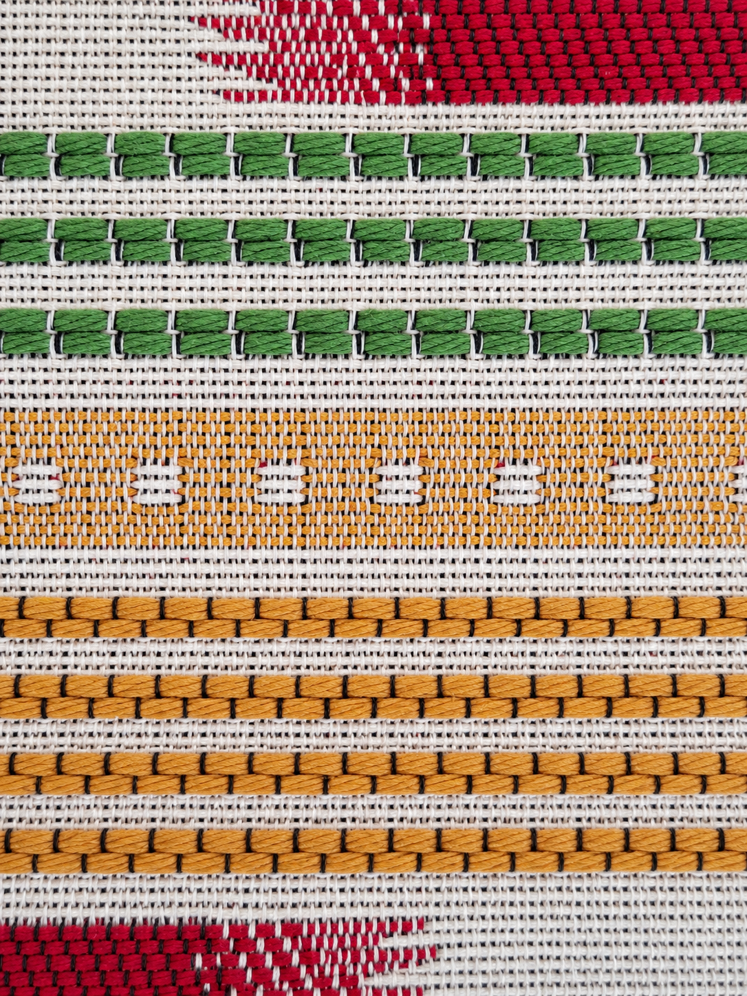 Detail geweven stof in groen, bordeauxrood, crème en oker